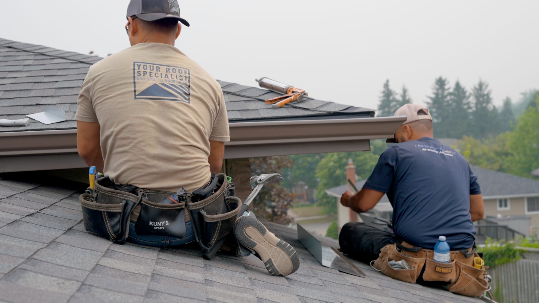 Two Your Roof Specialist crew members working together on a roof ridge during a repair in Kitchener-Waterloo