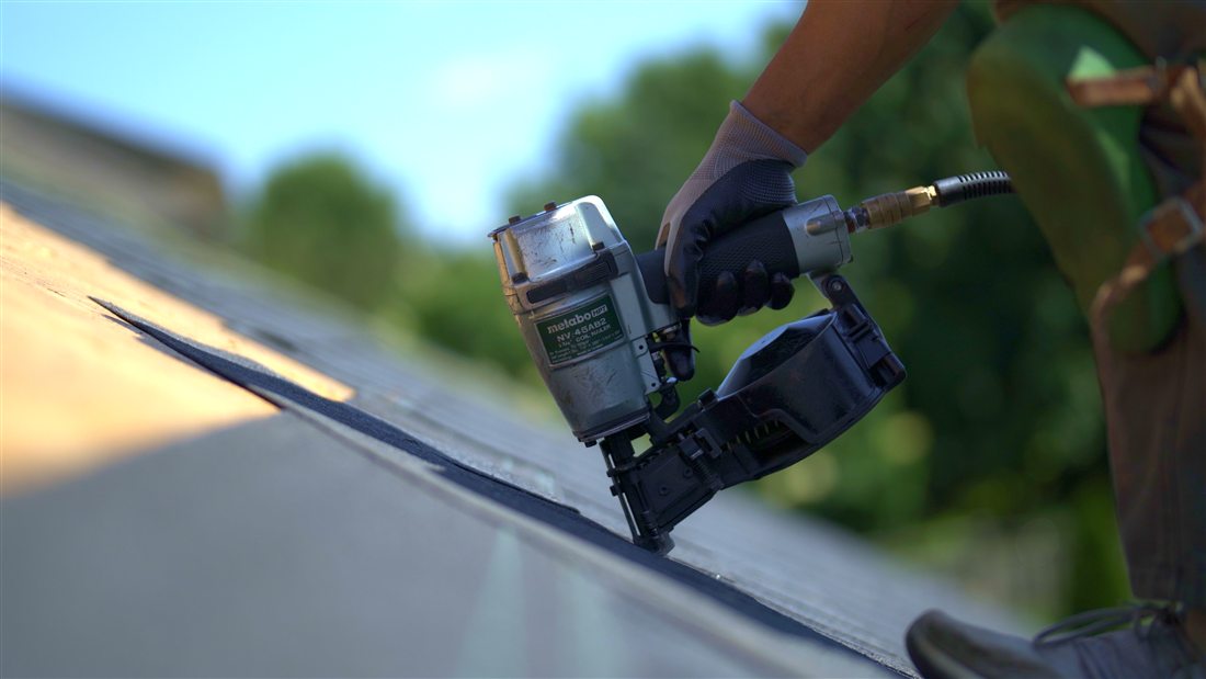 Your Roof Specialist crew member installing asphalt shingles with a pneumatic nail gun during a roof repair in Kitchener-Waterloo