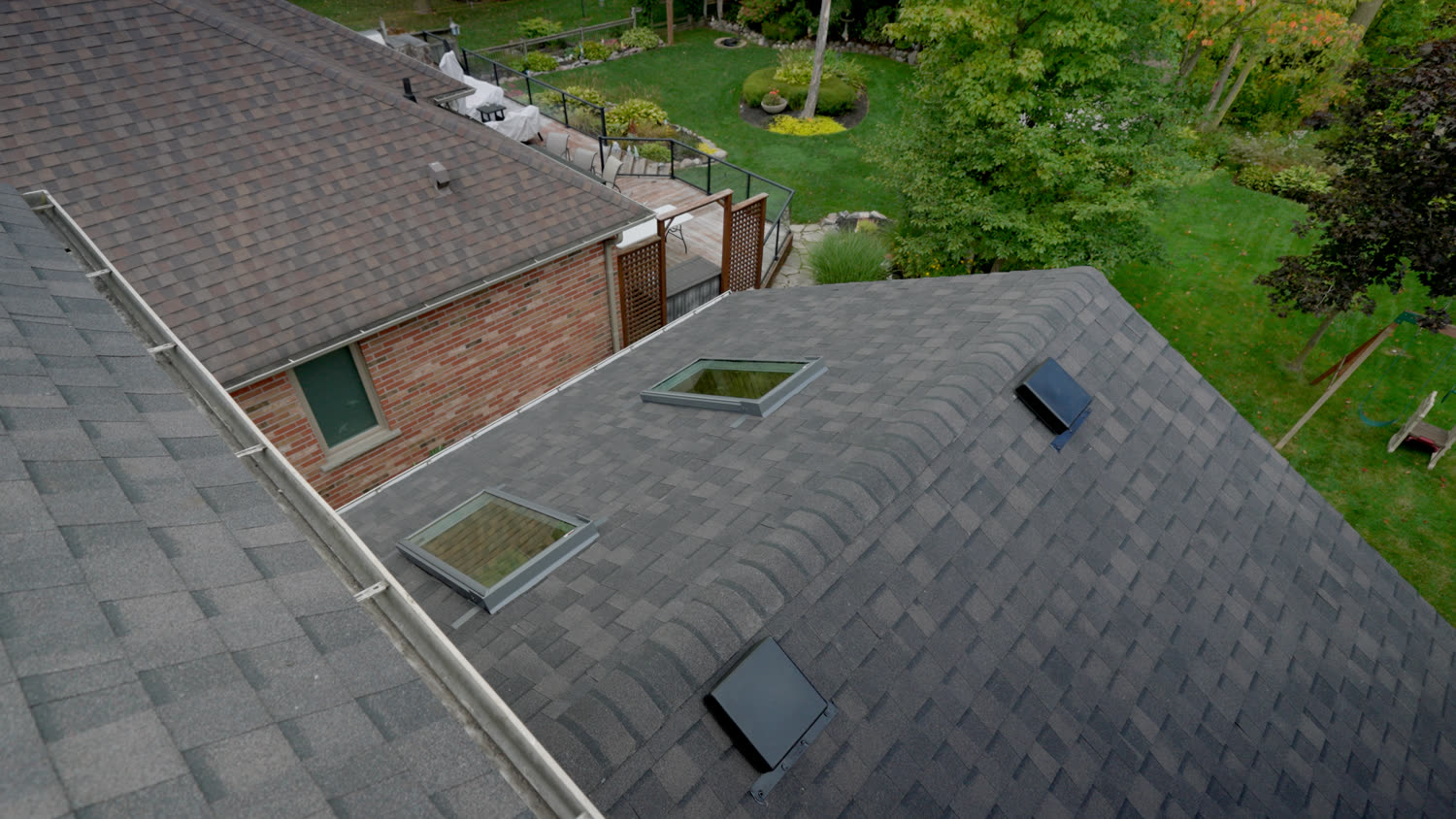 Aerial view of a finished charcoal shingle roof in Kitchener-Waterloo with two skylights and two box vents on the same slope